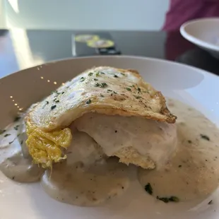 Biscuits and gravy with sausage gravy and an over hard egg