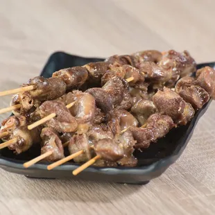 skewered meat on a black plate