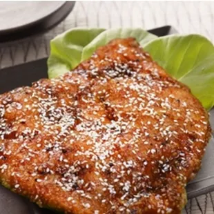 a large piece of meat on a plate with lettuce