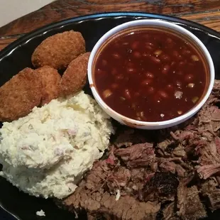 shows a plate of meat, beans, mashed potatoes, and