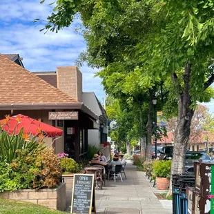 a sidewalk with tables and umbrellas
