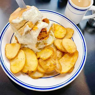 An awesome bear biscuit sandwich that's fried chicken, cheddar cheese and sawmill gravy with a side of home fries.