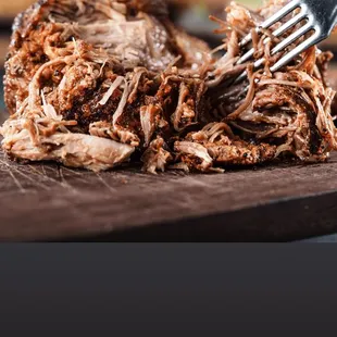 pulled pork on a cutting board with a fork