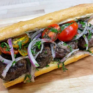 a meatball sandwich with tomatoes and onions