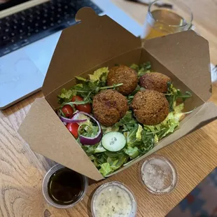 Falafel and green salad in a paper to-go box