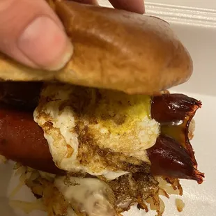 Hot link sandwich with eggs over easy, hash browns, and cheese