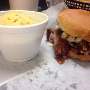 Pecan smoked brisket sandwich topped with coleslaw and a side of potato salad.