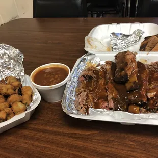 two trays of barbecued meat and sides