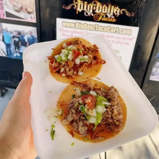 a person holding a plate of tacos