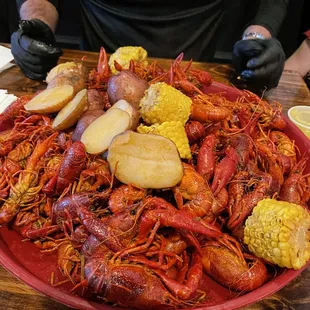 crawfish, corn, potatoes and corn on a red plate