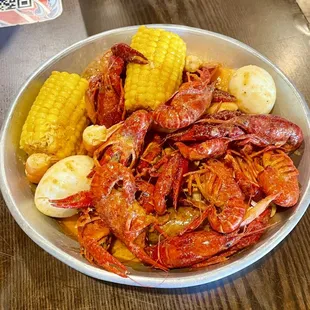 a bowl of crawfish, corn and potatoes