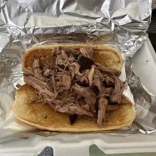 a pulled pork sandwich in a styrofoam container