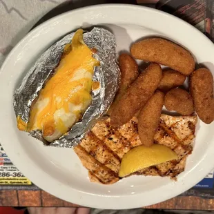 Grilled salmon meal with hush puppies and baked potato
