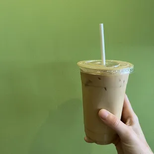 a hand holding a cup of iced coffee