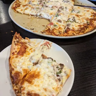 Combination pizza slices with whole pie in the background (large)