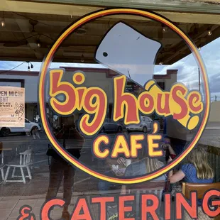the reflection of the restaurant&apos;s sign in the window