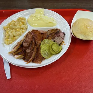 Three meat tray (Brisket, Turkey, Regular Sausage), Mac &amp; Cheese, Banana Pudding, pickles, and Dinner Roll.