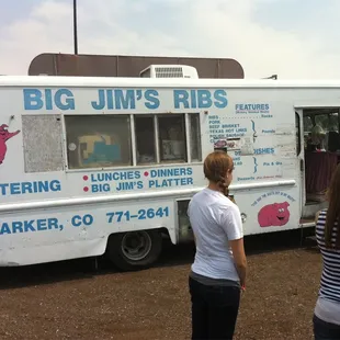 two women standing in front of a food truck