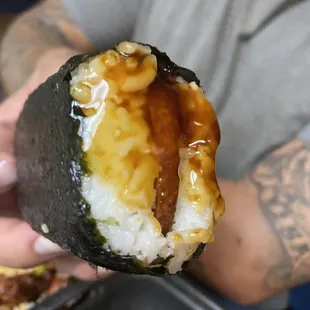 a person holding a piece of sushi