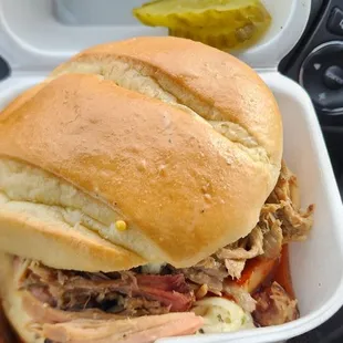 ows a pulled pork sandwich in a styrofoam container