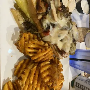 Chicken Philly cheesesteak sandwich with waffle fries and seasoned sour cream