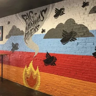a brick wall with a mural of a flame and birds