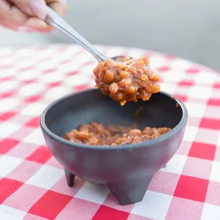 a hand holding a spoon full of bbq sauce