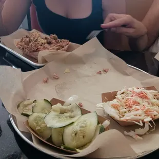 Plain pulled chicken in tray furthest away, with cucumbers and Cole slaw