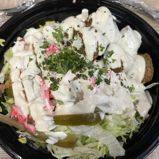 Falafel bowl. Pickled vegetables,yellow rice, lettuce, tomatoes covered in house made tahini ranch sauce and topped with fresh parsley.