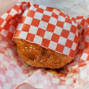 a hamburger wrapped in red and white checkered paper