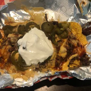 Beef brisket nachos with jalapeños &amp; whip cream.