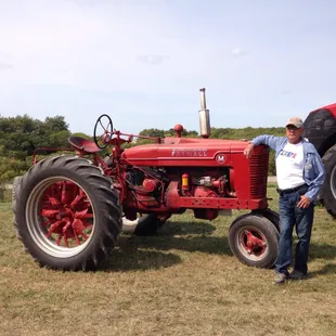 a man standing next to a red tractor