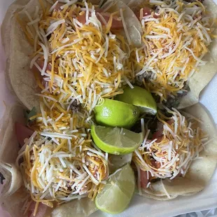 Asada tacos with cheese and tomatoes, salsa and lime
