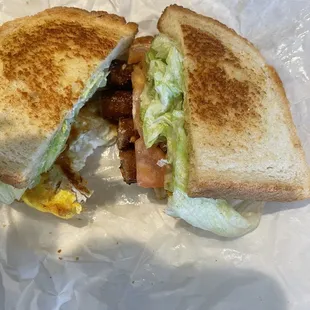 Breakfast sausage, eggs, cheese, tomatoes, lettuce on white bread