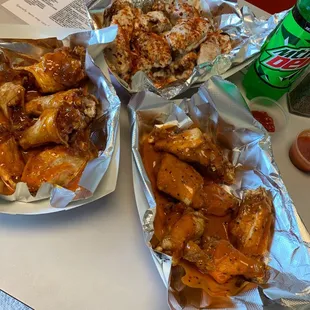 two trays of wings and a bottle of soda