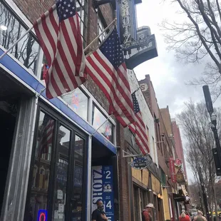 people walking down the sidewalk in front of a store