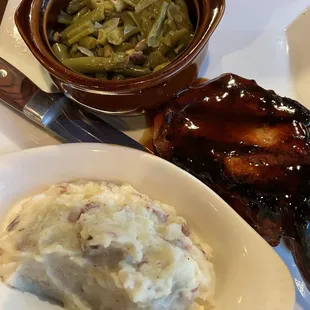 Barbecued pork chops with mashed potatoes and green beans.
