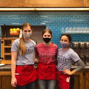 three girls wearing masks and aprons