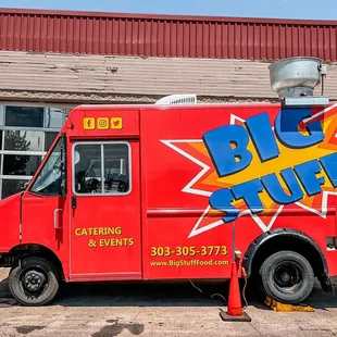 a red food truck parked in front of a building