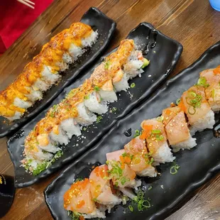 three plates of sushi on a wooden table