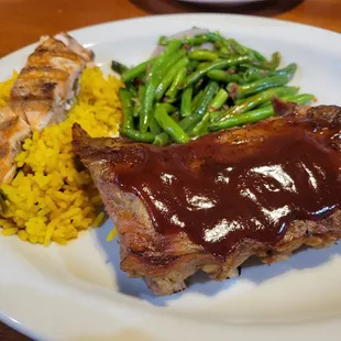 a plate of meat, rice and green beans