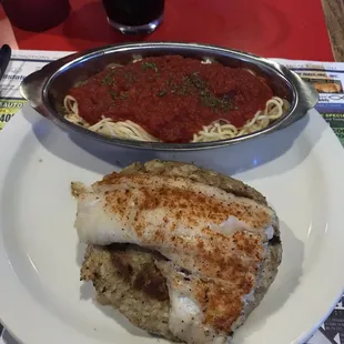 Crab cake between two halibut fillets and pasta side.