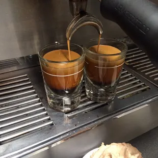 two cups of coffee being poured into a cup