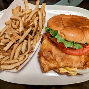 Sizeable fish sandwich with fries.