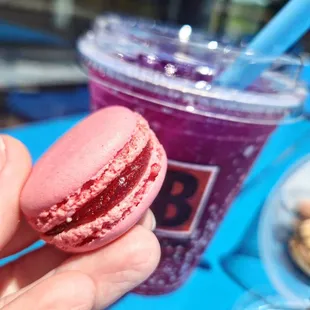 a hand holding a pink macaron