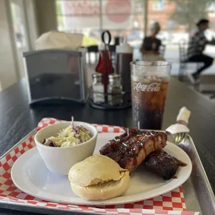 Pork ribs, homemade coleslaw, and a delicious dinner Roll with an ice cold Coca-Cola drink.