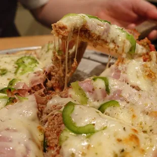 a person taking a slice of pizza