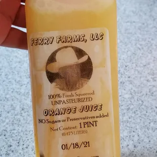 a hand holding a bottle of orange juice