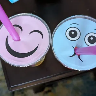 two cups with smiley faces and a straw