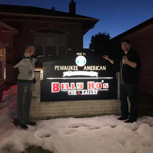 two men standing in front of a sign